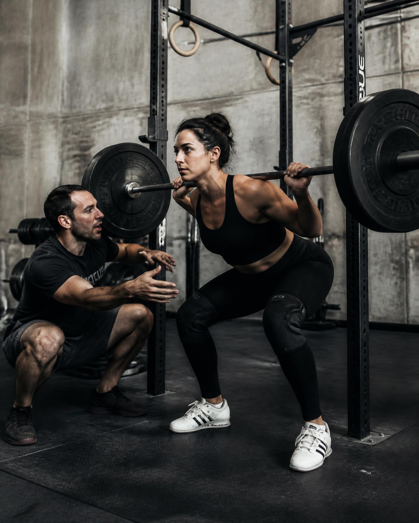 Coach cueing an athlete through a barbell back squat