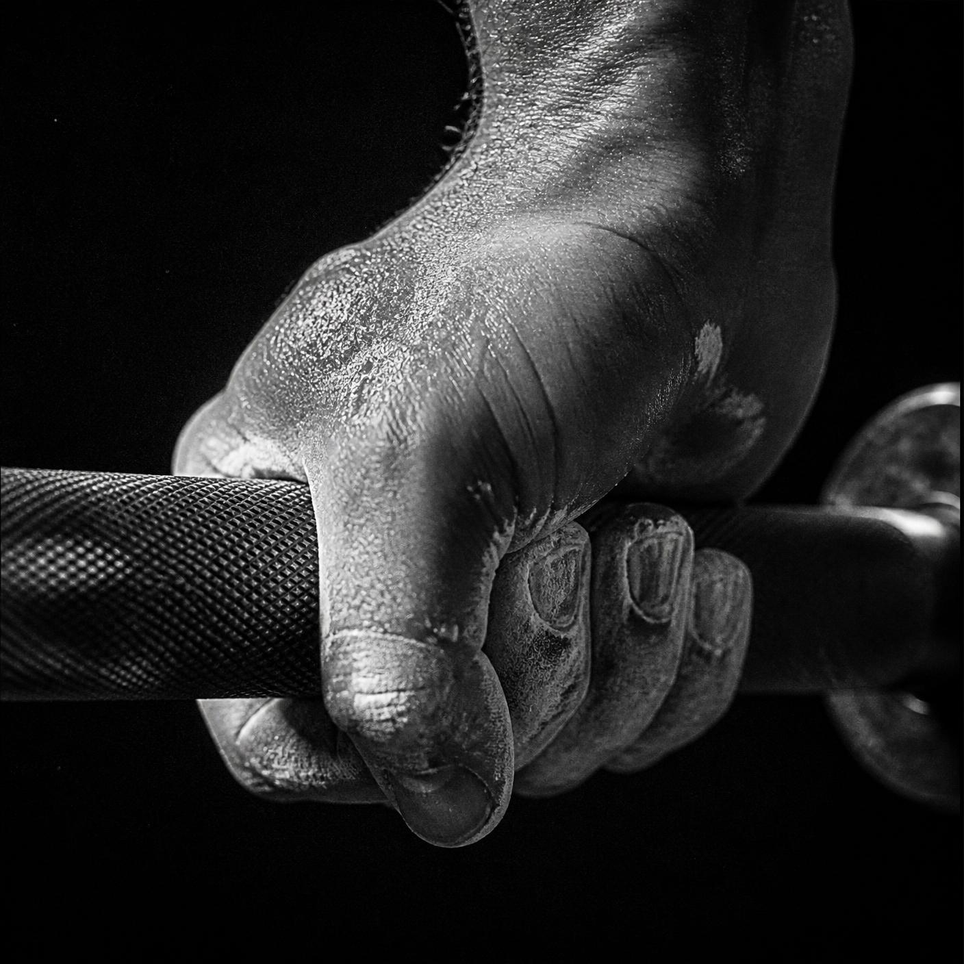 Chalked hand gripping a knurled barbell